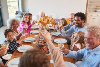 Multi-Generation Family Making A Toast With Wine As They Meet For Meal At Home