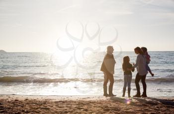 Rear View Of Grandmother With Mother And Granddaughters Standing Silhouetted By Sea