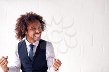 Happy Young Businessman Wearing Suit Celebrating Standing Against White Studio Wall
