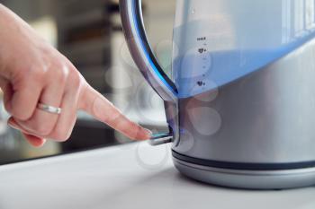 Close Up Of Woman Pressing Power Switch On Electric Kettle To Save Energy At Home