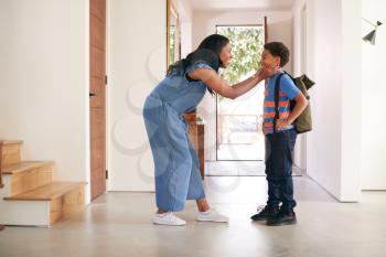 Mother Saying Goodbye To Son As He Leaves Home For School