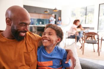 Loving African American Father And Son Sitting On Sofa At Home Together
