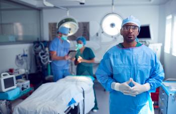 Portrait Of Male Surgeon Wearing Scrubs And Protective Glasses In Hospital Operating Theater