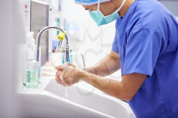 Male Surgeon Wearing Scrubs Washing Hands Before Operation In Hospital Operating Theater