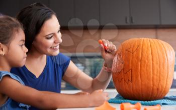 Mother And Daughter Carving Halloween Lantern From Pumpkin At Home