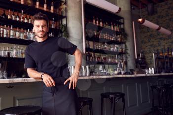 Portrait Of Confident Male Owner Of Restaurant Bar Leaning Against Counter