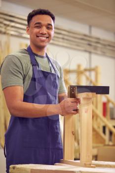 Portrait Of Male Student Studying For Carpentry Apprenticeship At College Using Set Square