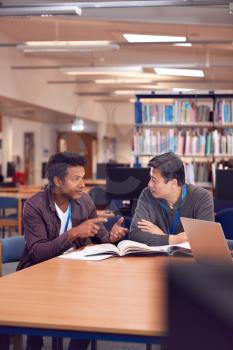 Teacher With Mature Male Adult Student Sitting At Table Working In College Library