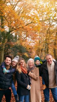 Portrait Of Smiling Multi-Generation Family Walking Along Autumn Woodland Path