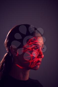 Facial Recognition Technology Concept As Woman Has Red Grid Projected Onto Face In Studio