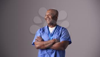 Studio Portrait Of Male Nurse Wearing Scrubs Standing Against Grey Background