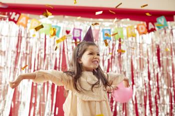 Girl In Party Hat Celebrating At Birthday Party With Streamers And Gold Confetti