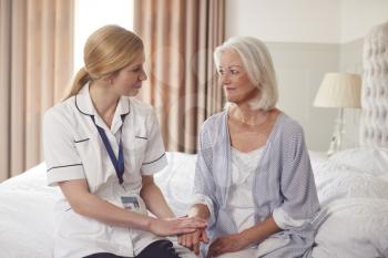 Female Doctor Making Home Visit To Senior Woman For Medical Check Offering Reassurance