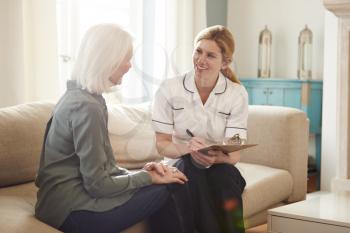 Female Doctor Making Home Visit To Senior Woman For Medical Check