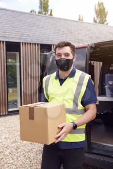 Portrait Of Delivery Driver Wearing Mask Holding Package Outside House