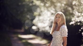 Portrait Of Smiling Woman Wearing Summer Dress Walking Along Countryside Path