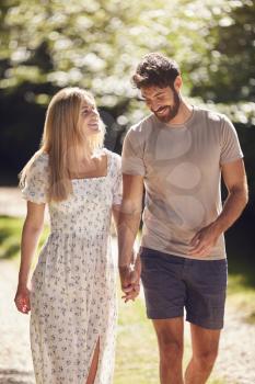 Loving Couple Walking Holding Hands Along Countryside Path In Summer Together