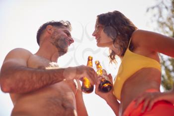 Couple Wearing Swimming Costumes Standing In Summer Garden At Home Drinking Beer