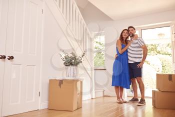 Mature Couple With Boxes Standing By Front Door Of New Home On Moving Day
