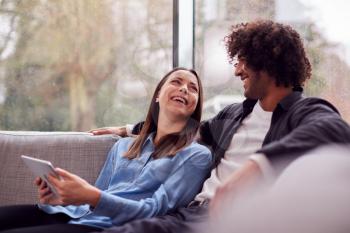 Relaxed Young Couple At Home Lying On Sofa With Digital Tablet