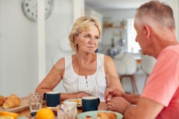 Senior Man Comforting Woman Suffering With Depression At Breakfast Table At Home