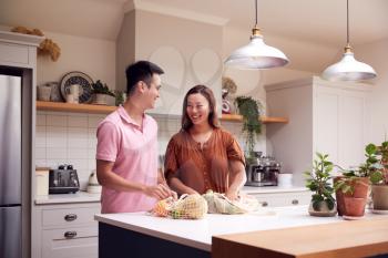 Asian Couple Unpacking Local Food In Zero Waste Packaging From Bag In Kitchen At Home