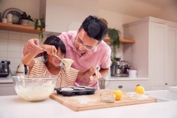 Asian Father And Daughter Making Cupcakes In Kitchen At Home Together