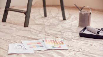 Close Up Of Color Charts With Paint Roller And Step Ladder In Room Being Decorated