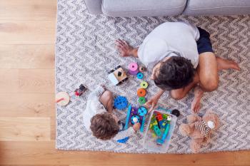Overhead Shot Of Father And Young Son Playing With Toys On Rug At Home
