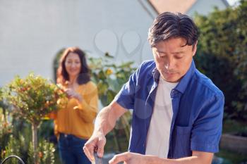 Close Up Of Mature Asian Couple At Work Watering And Caring For Plants In Garden At Home