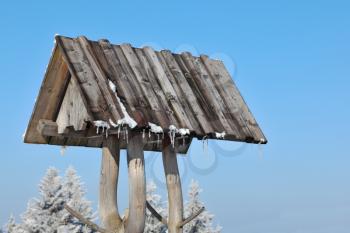 A bright sunny winter morning in the Tatras. Roof of a rural well with icicles