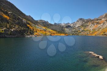 Mountain fishing lake with transparent azure water. Solar autumn midday