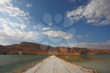 Sunset. Incredible lighting effects in a thunderstorm at the Dead Sea. The road in the middle of the sea
