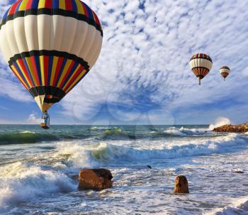 Huge balloons with the passenger basket flying over the sea shore. Mediterranean Sea, a spring storm
