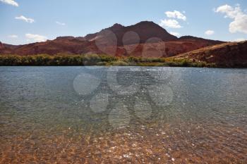 Bottling the Colorado River.  Mountain of red sandstone  and thin water ripples 
