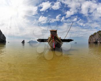 The well-known Thai boat Longtail is moored by an anchor on sand. A picturesque sandy beach on ocean island. Thailand
