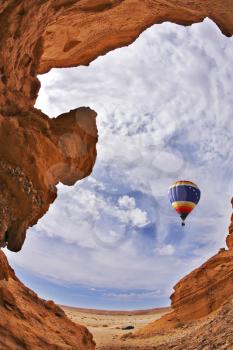 The balloon flies above a picturesque slot-hole canyon in desert