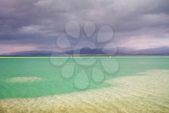 Sunset. Incredible lighting effects in a thunderstorm at the Dead Sea. Multi-colored water in the shallows
