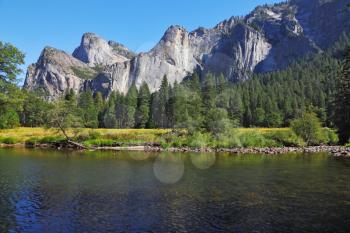 Shallow Merced River, surrounded by mountains, in the famous Yosemite Park