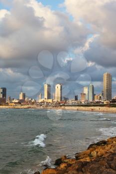 The fluffy clouds shined with the sunset sun, over magnificent hotels of quay in Tel Aviv.
