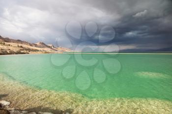 Sunset. Incredible lighting effects in a thunderstorm at the Dead Sea. Multi-colored water in the shallows