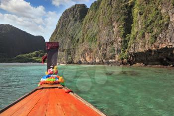 Thailand sightseeing boat sails in the picturesque bay. Bow is decorated with colorful and bright silk scarves
