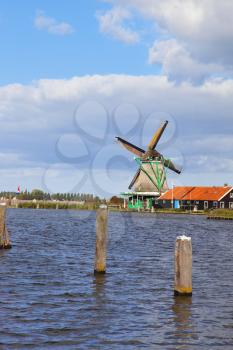 Traditional windmills and berthing bumpers on coast of the channel in Holland.
