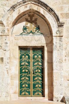 Entrance to the Coptic Church of the Holy Sepulchre in Ierusalime.Green doors are decorated by gold grape clusters and pomegranates