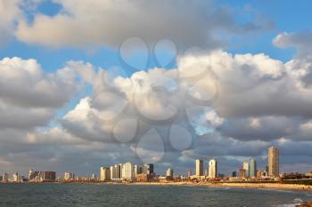 The magnificent hotels of quay in Tel Aviv. The fluffy clouds shined with the sunset sun