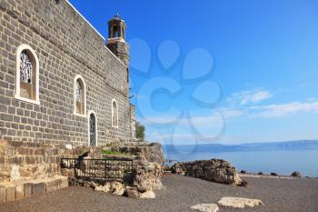 One of the oldest churches in the Sea of Galilee. Stone wall of black stones on a smooth slope to the lake water
