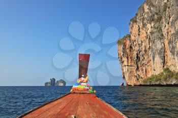 The Thai excursion boat floats to ocean island. The boat nose is decorated by multi-colored and bright silk scarfs