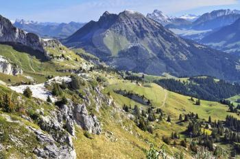 Magnificent Swiss Alps in early autumn. Green alpine meadows side by side with the first light snow

