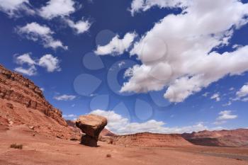 American rock desert. The famous giant mushroom of red sandstone, glowing clouds, midday shadows