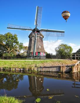 Over the windmills in the sky flying a giant balloon. The bright summer day in Holland